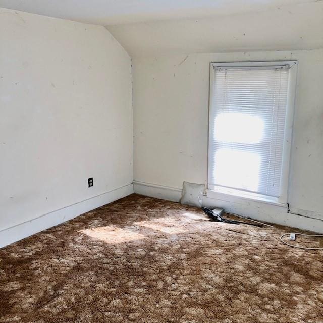 carpeted spare room with lofted ceiling