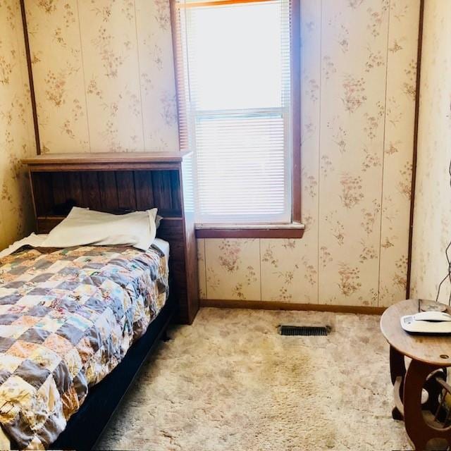 carpeted bedroom featuring visible vents, baseboards, and wallpapered walls