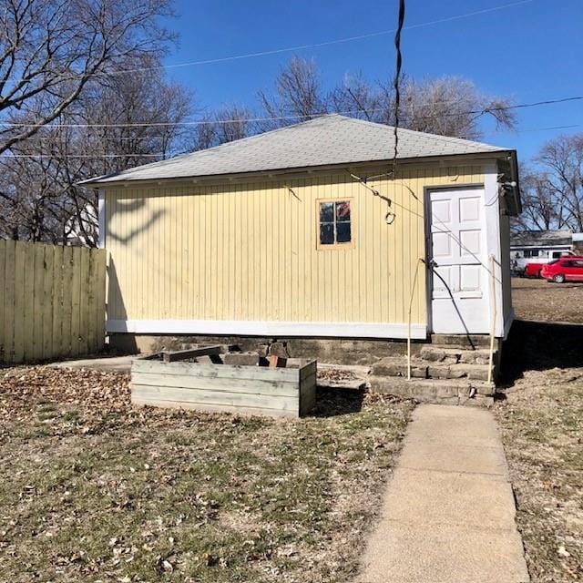 view of property exterior featuring fence and roof with shingles