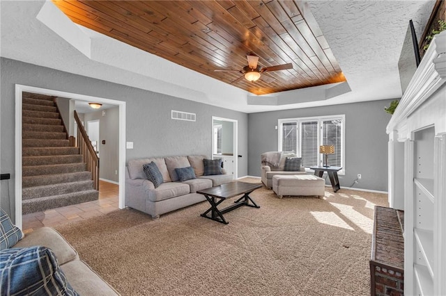 living area featuring visible vents, a tray ceiling, carpet flooring, wooden ceiling, and a textured wall