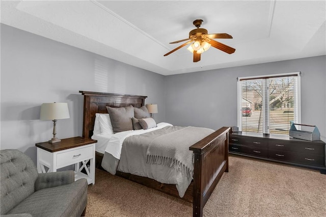 bedroom with a tray ceiling, carpet floors, and a ceiling fan