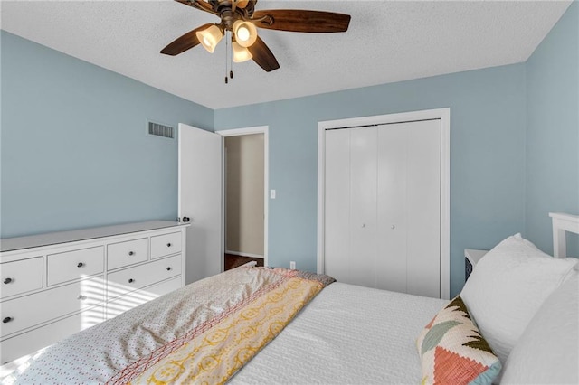 bedroom featuring a closet, visible vents, a textured ceiling, and a ceiling fan