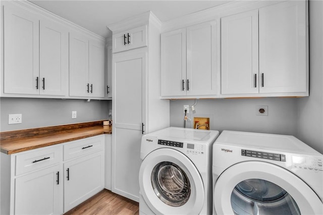 laundry room featuring cabinet space, light wood-type flooring, and separate washer and dryer