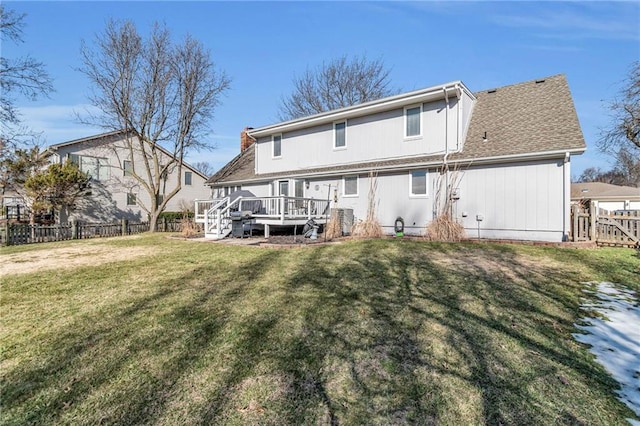 back of property with a shingled roof, a yard, fence, and a wooden deck