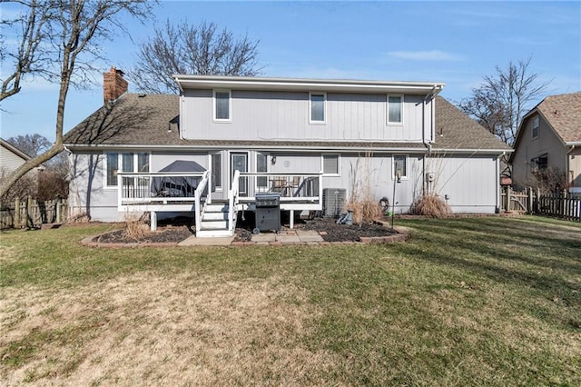 rear view of property with a wooden deck, a chimney, a yard, and fence