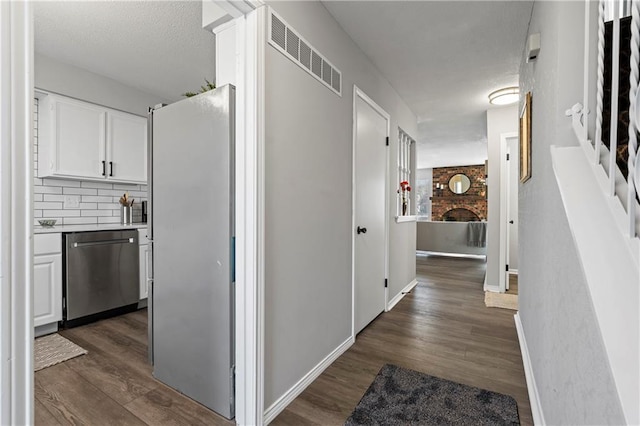 hallway featuring visible vents, dark wood finished floors, and baseboards