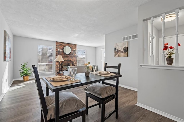 dining room with baseboards, visible vents, dark wood finished floors, and a fireplace