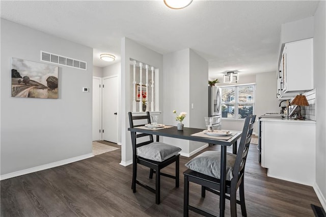 dining space with dark wood-style floors, baseboards, and visible vents