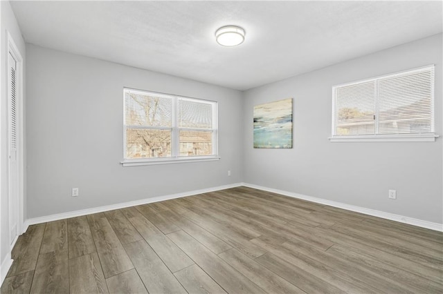 spare room with plenty of natural light, wood finished floors, and baseboards