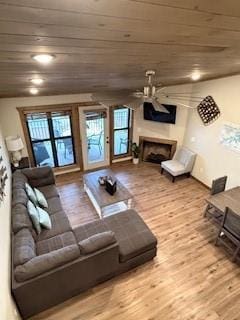 living room featuring wooden ceiling, ceiling fan, a fireplace, and wood finished floors