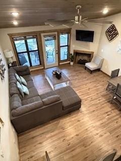 living room featuring a healthy amount of sunlight, a fireplace, a ceiling fan, and wood finished floors