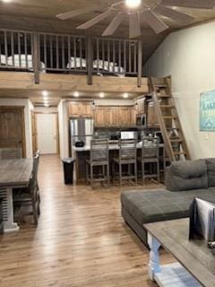 living room featuring a ceiling fan, a towering ceiling, and light wood finished floors