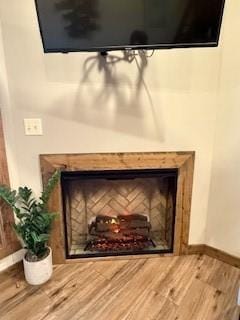 interior details with a fireplace, baseboards, and wood finished floors