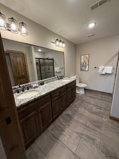 bathroom featuring double vanity, visible vents, toilet, a shower stall, and a sink