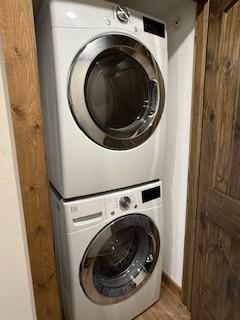 laundry room featuring light wood-type flooring, stacked washer and dryer, and laundry area