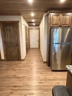 interior space with light wood-type flooring, wooden ceiling, light stone counters, and freestanding refrigerator