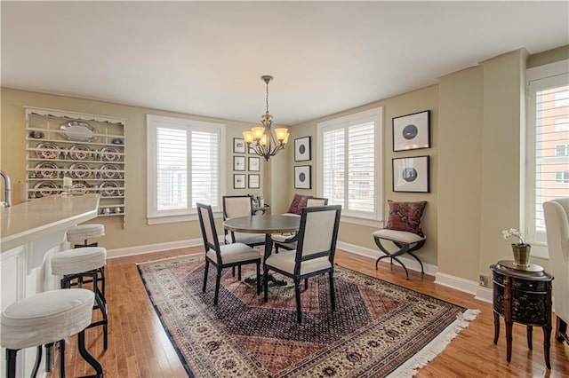 dining area featuring a chandelier, wood finished floors, and baseboards