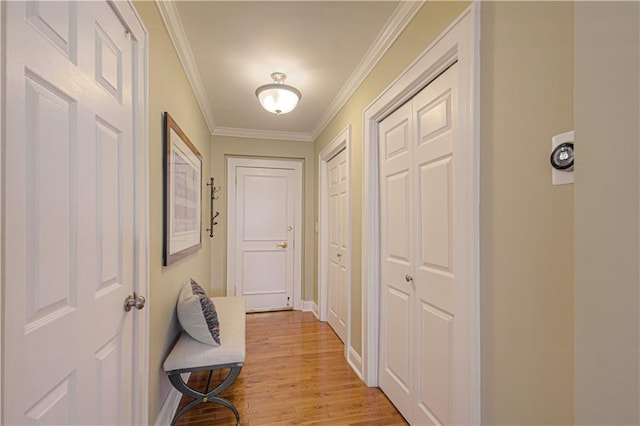 hall with light wood-type flooring, baseboards, and crown molding