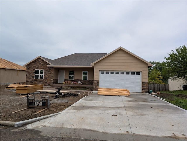 1107 Charles St, Knob Noster, MO 65336 - ranch-style house featuring stone siding, an attached garage, driveway, roof with shingles, and covered porch