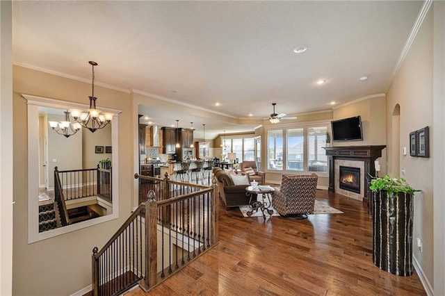 living room with crown molding, a fireplace, baseboards, and wood finished floors