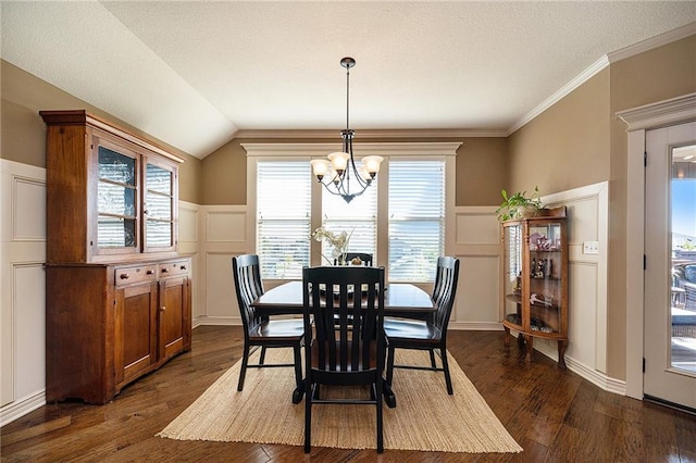 dining room featuring a wainscoted wall, dark wood finished floors, a decorative wall, an inviting chandelier, and vaulted ceiling