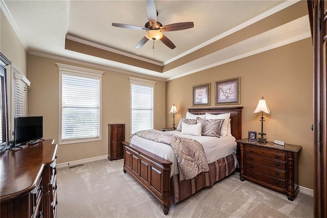 bedroom with a tray ceiling, light colored carpet, ornamental molding, ceiling fan, and baseboards