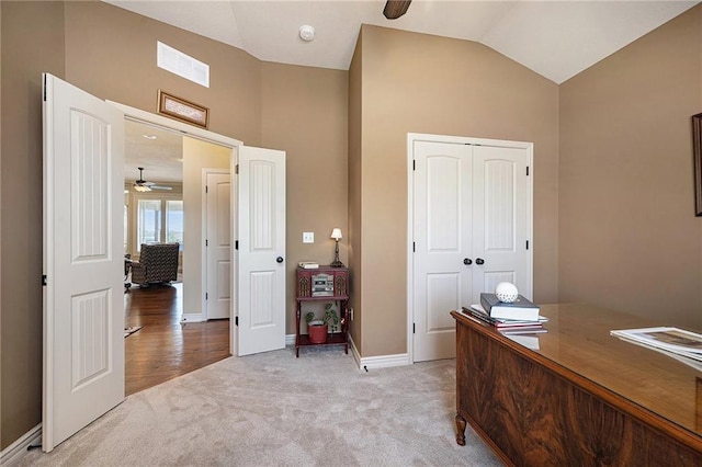 office space featuring light carpet, baseboards, visible vents, a ceiling fan, and vaulted ceiling