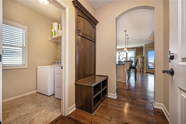 clothes washing area featuring arched walkways, laundry area, dark wood finished floors, and baseboards