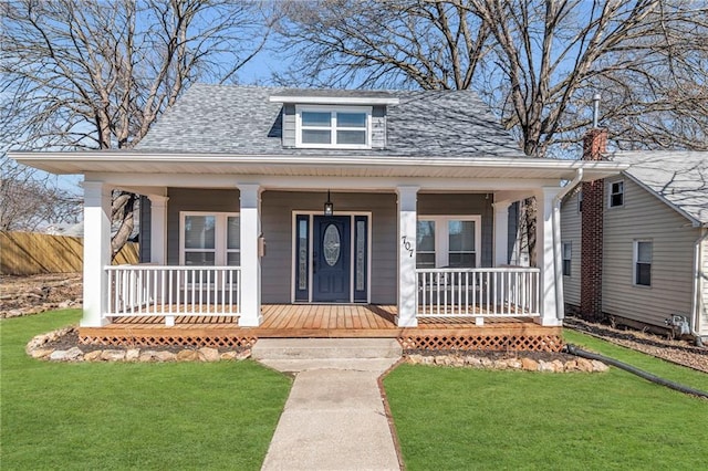 bungalow-style home featuring covered porch, a shingled roof, fence, and a front lawn