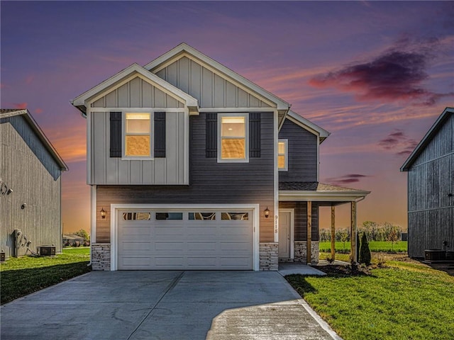 view of front of home featuring a garage, stone siding, a front lawn, and board and batten siding