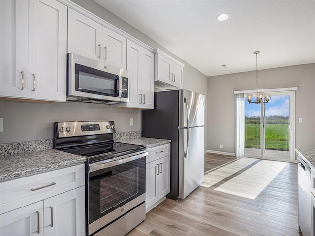 kitchen with stainless steel appliances, light stone counters, light wood-style flooring, and white cabinets