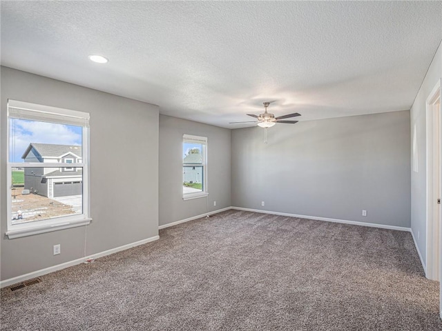 carpeted empty room featuring baseboards, visible vents, ceiling fan, and a textured ceiling