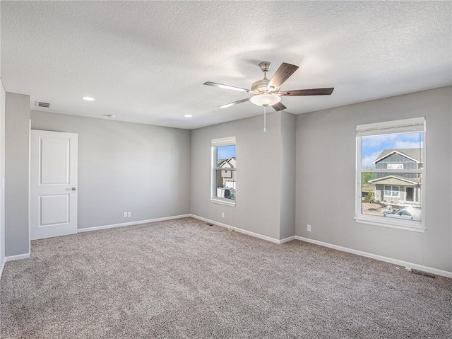 carpeted spare room with baseboards, visible vents, and a healthy amount of sunlight