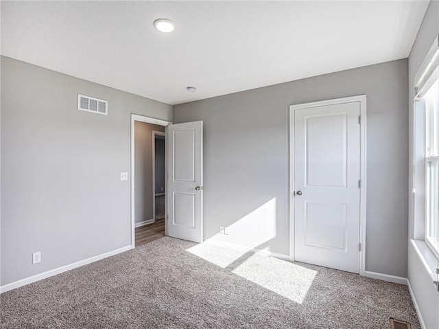 unfurnished bedroom featuring carpet, visible vents, and baseboards