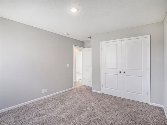 unfurnished bedroom featuring carpet floors, a closet, visible vents, and baseboards