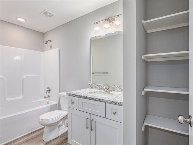 bathroom featuring visible vents, toilet, wood finished floors, bathtub / shower combination, and vanity