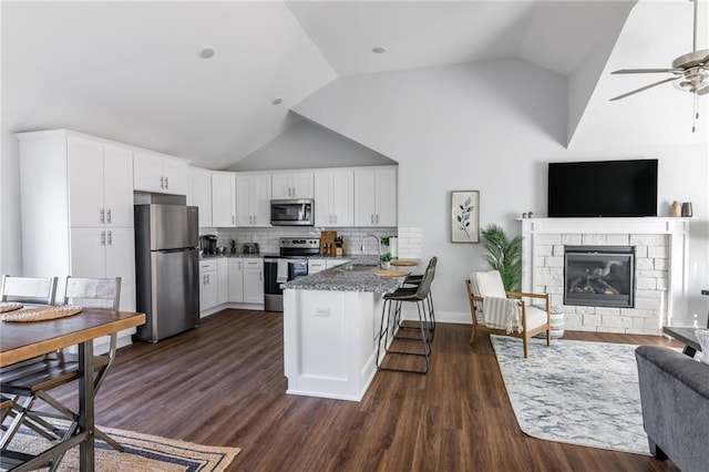 kitchen featuring a sink, open floor plan, white cabinetry, stainless steel appliances, and a peninsula