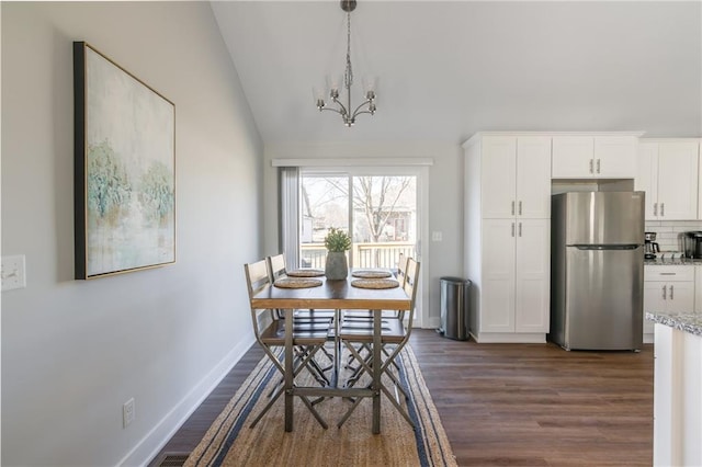 dining space featuring dark wood finished floors, a notable chandelier, lofted ceiling, and baseboards