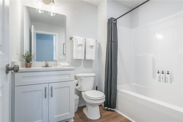 bathroom featuring shower / bath combo with shower curtain, toilet, vanity, and wood finished floors