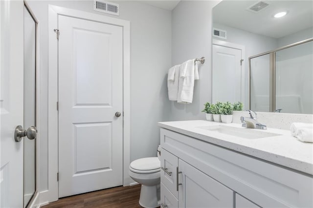 bathroom with visible vents, a stall shower, toilet, and wood finished floors