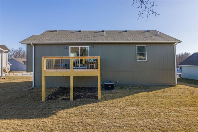 back of house featuring a lawn, roof with shingles, and a wooden deck