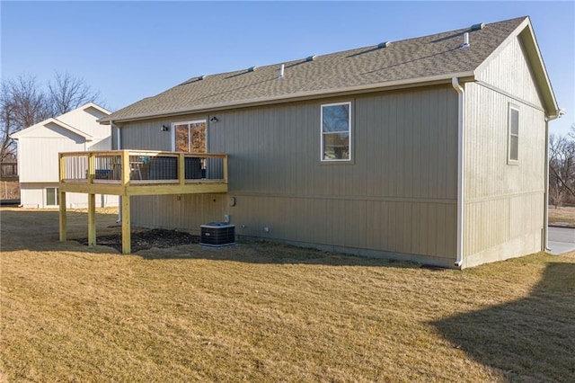 back of property with a wooden deck, a lawn, and roof with shingles