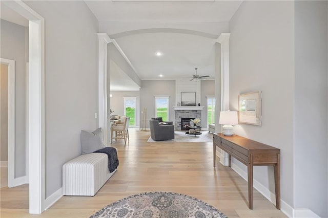 corridor with arched walkways, recessed lighting, baseboards, and light wood-style floors