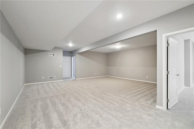 finished below grade area featuring baseboards, visible vents, and light colored carpet