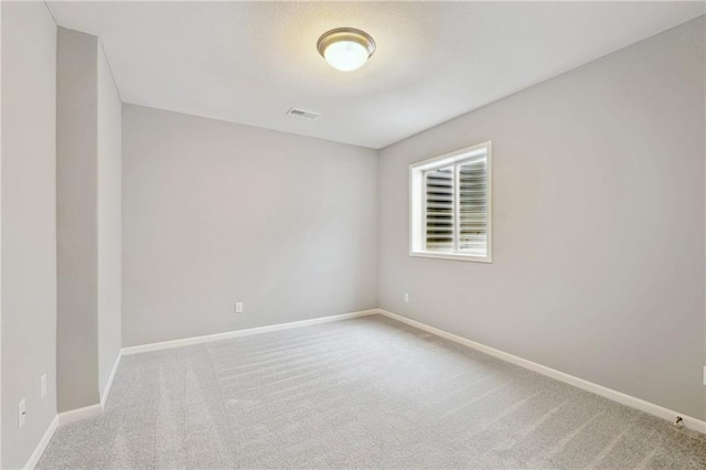 carpeted spare room with visible vents and baseboards