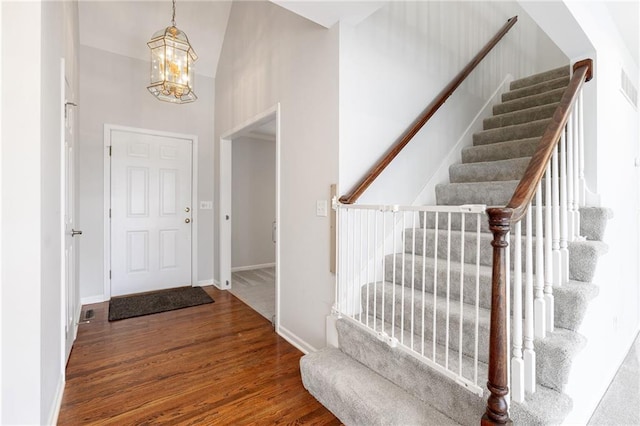 foyer with visible vents, a notable chandelier, wood finished floors, baseboards, and stairs