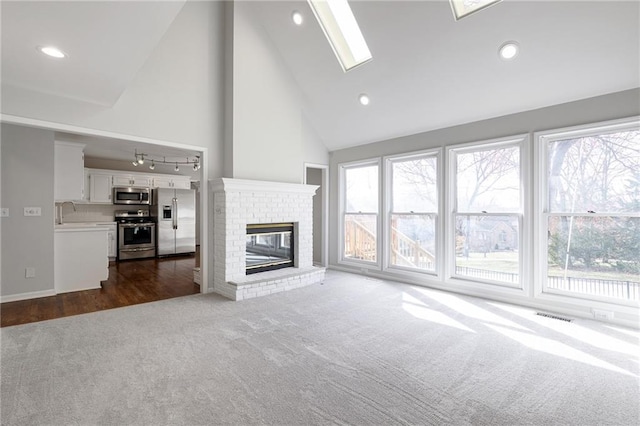 unfurnished living room with visible vents, high vaulted ceiling, dark carpet, recessed lighting, and a brick fireplace