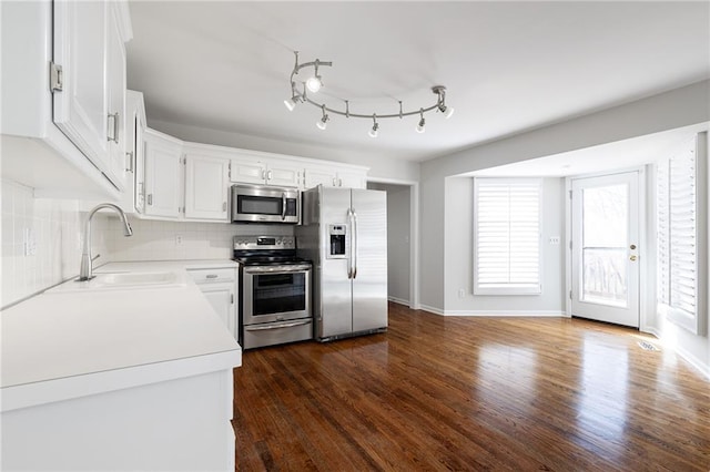 kitchen featuring a sink, decorative backsplash, dark wood-type flooring, light countertops, and stainless steel appliances