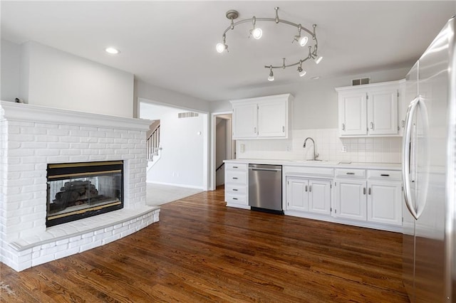 kitchen featuring backsplash, stainless steel dishwasher, refrigerator, dark wood finished floors, and light countertops