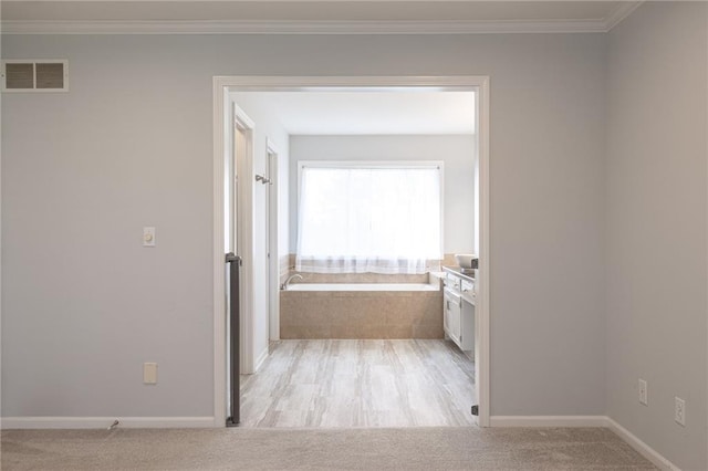 hall with light carpet, visible vents, baseboards, and ornamental molding